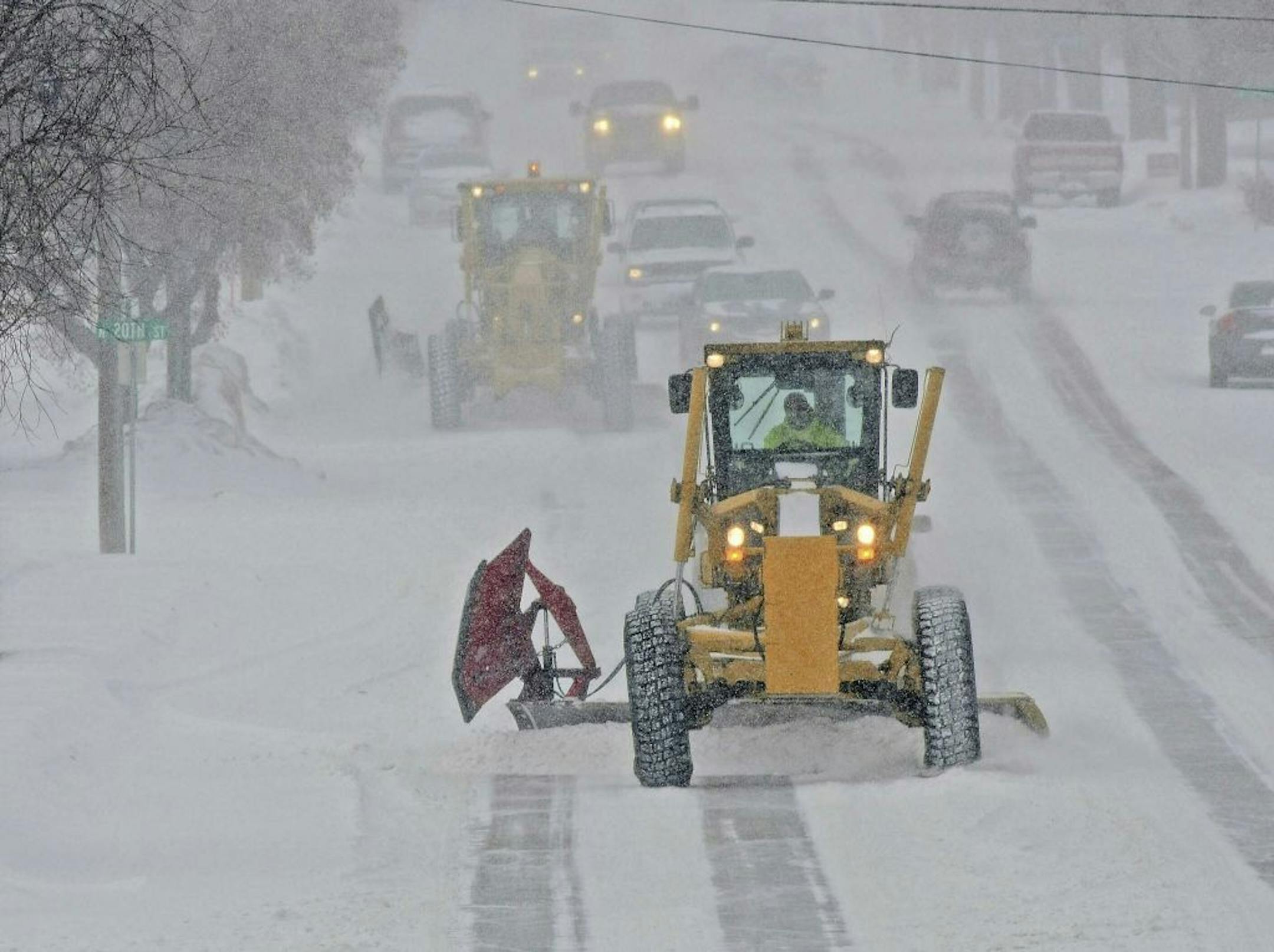 Motor graders plow Rosser Avenue as snow falls, Friday, Jan. 18, 2019, in Bismarck, N.D.