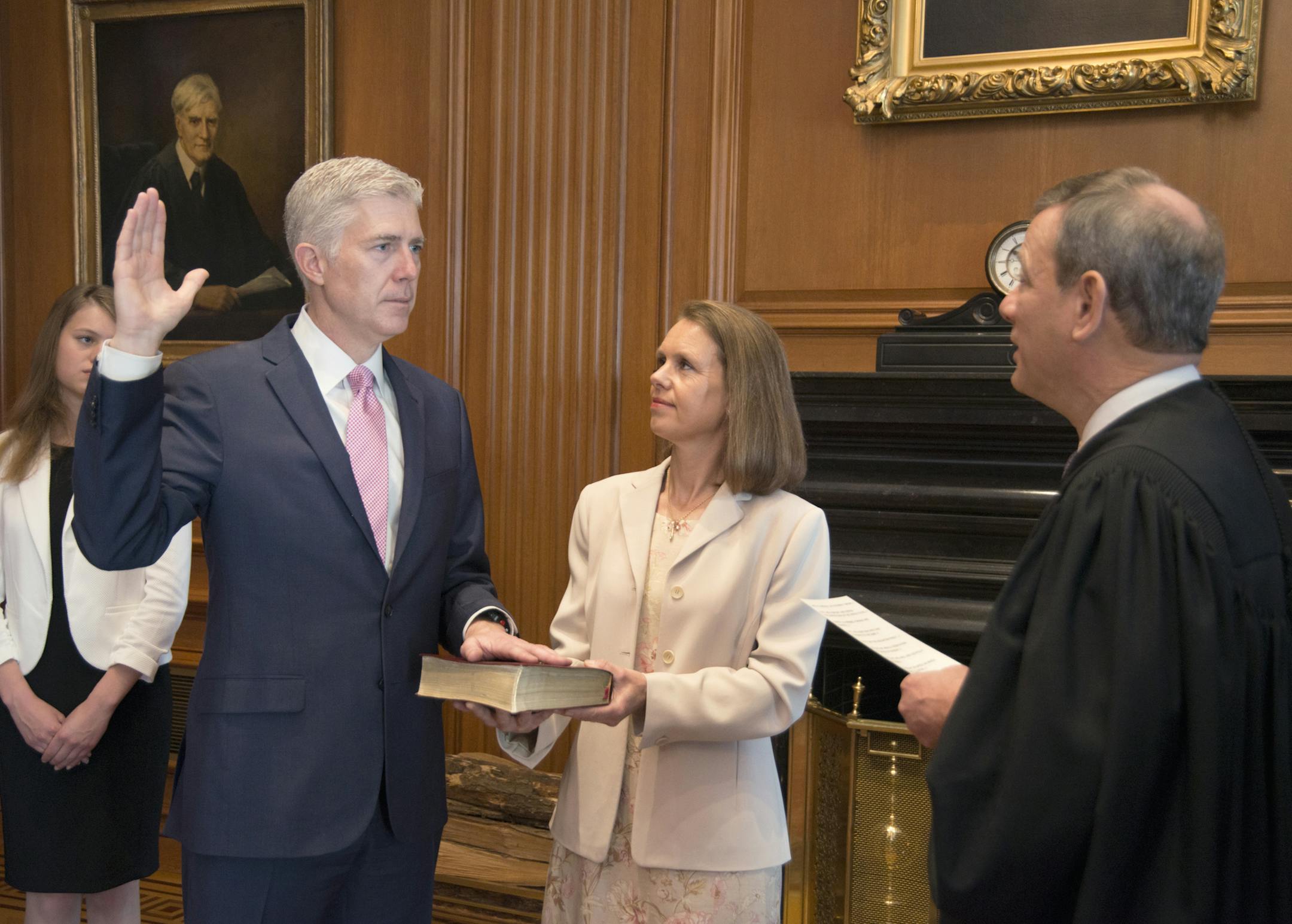 In this photo provided by the Public Information Office Supreme Court of the U.S. Chief Justice John G. Roberts, Jr., administers the Constitutional Oath to the Neil Gorsuch in a private ceremony attended by the Justices of the Supreme Court and members of the Gorsuch family, including wife Louise Gorsuch, Monday, April 10, 2017, in the Justices' Conference Room at the Supreme Court in Washington. Surrounded by family and his soon-to-be Supreme Court colleagues, Gorsuch took the first of two oat
