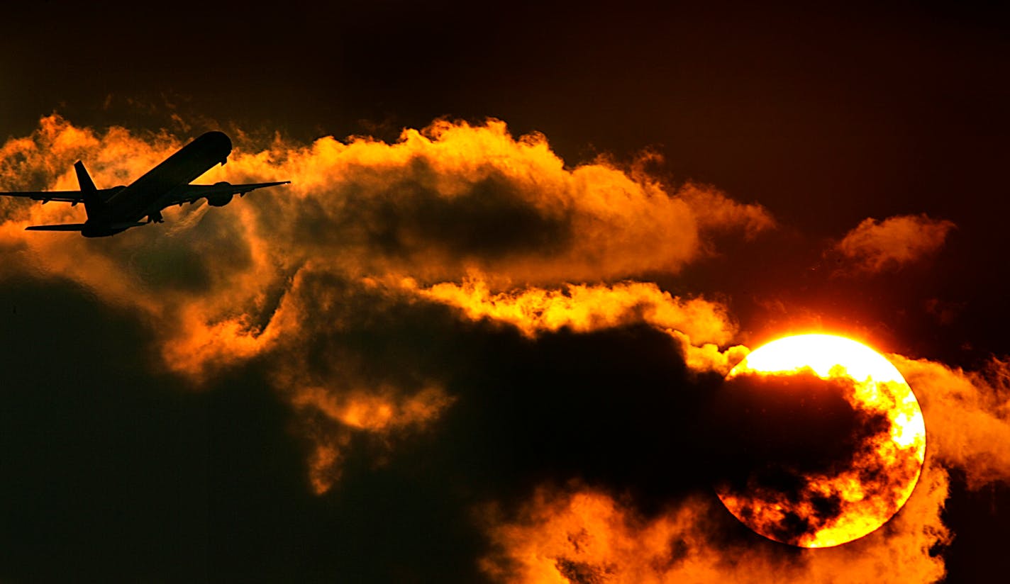 The setting sun provides a dramatic backdrop to a Northwest Airlines jet as it soars into the clouds during takeoff from Minneapolis-St. Paul International Airport.