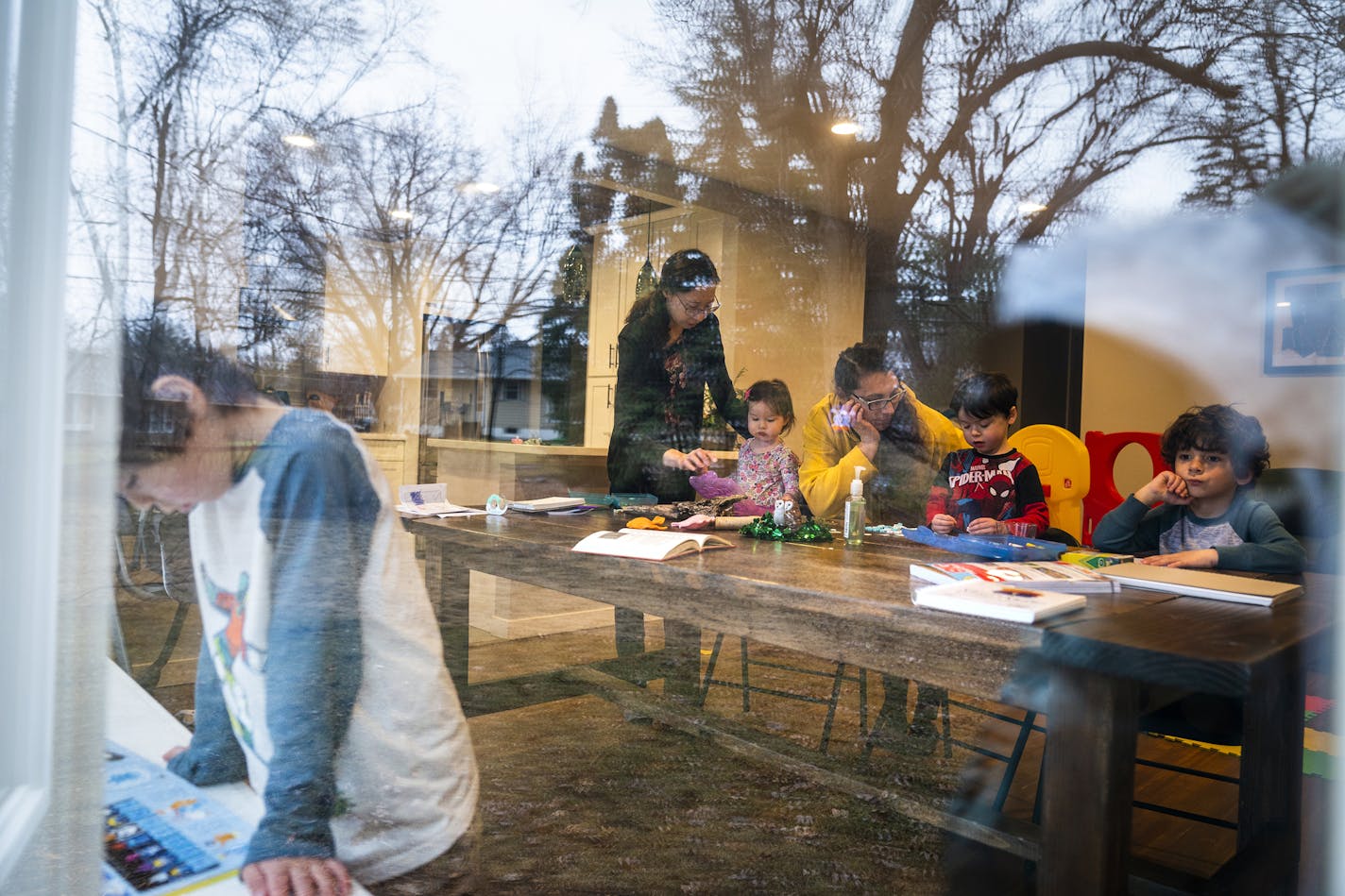 In this Wednesday, March 25, 2020, photo, Andrea Royce, standing at center, homeschools her children Rowan, from left, 6, Lucy, 1, and Parker, 4, with the help of friend Carlota Bernal, third from right, who helps with childcare, with her son Blaze Boxell, far right, in Roseville, Minn. Parents are taking on the role of educators now that the schools are closed due to the new coronavirus pandemic. (Leila Navidi/Star Tribune via AP)