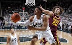 Michigan State's Miles Bridges, center, puts up a reverse layup against Minnesota's Reggie Lynch (22) as Michigan State's Kenny Goins, left, watches d