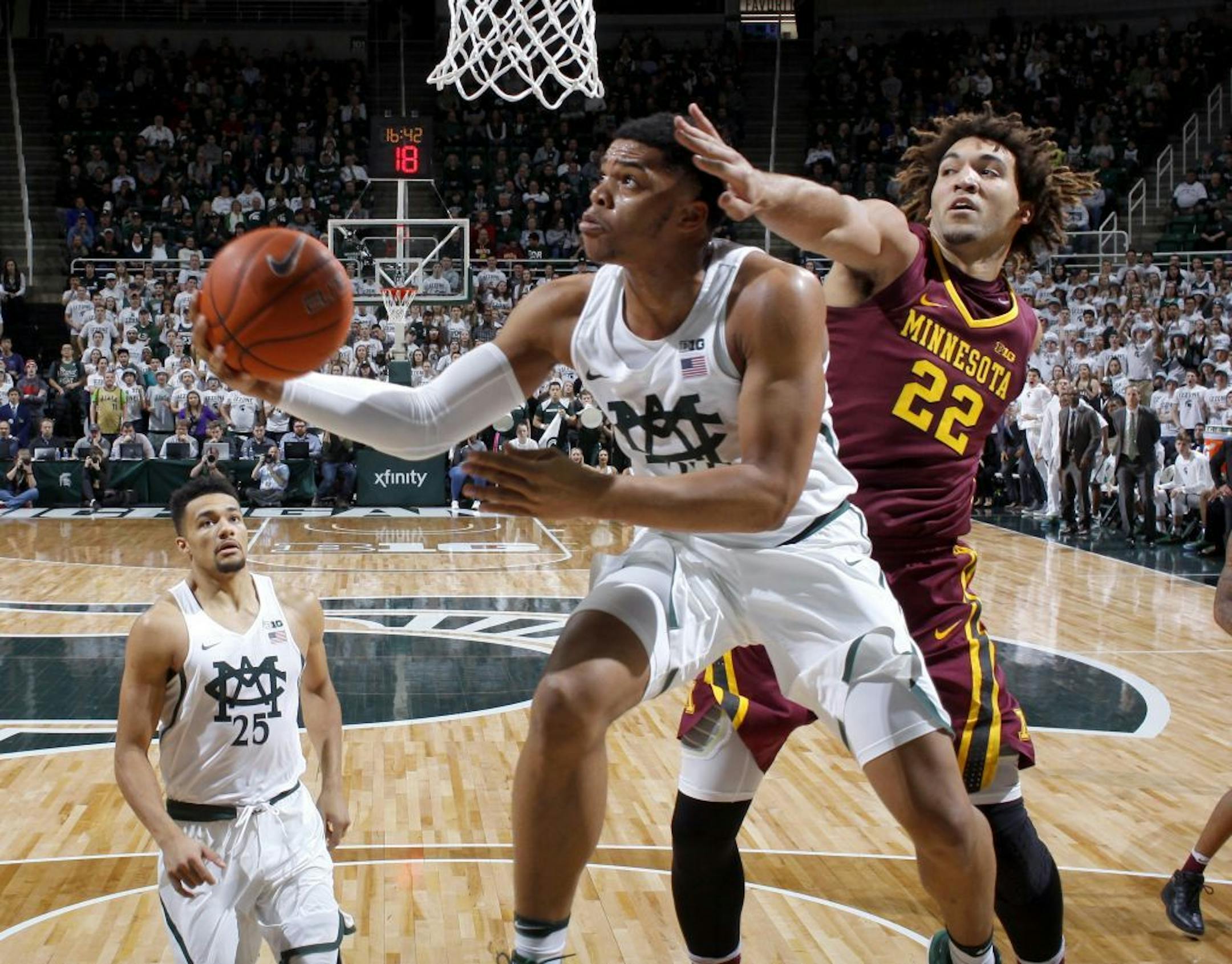 Michigan State's Miles Bridges, center, puts up a reverse layup against Minnesota's Reggie Lynch (22) as Michigan State's Kenny Goins, left, watches during the first half of an NCAA college basketball game, Wednesday, Jan. 11, 2017, in East Lansing, Mich.