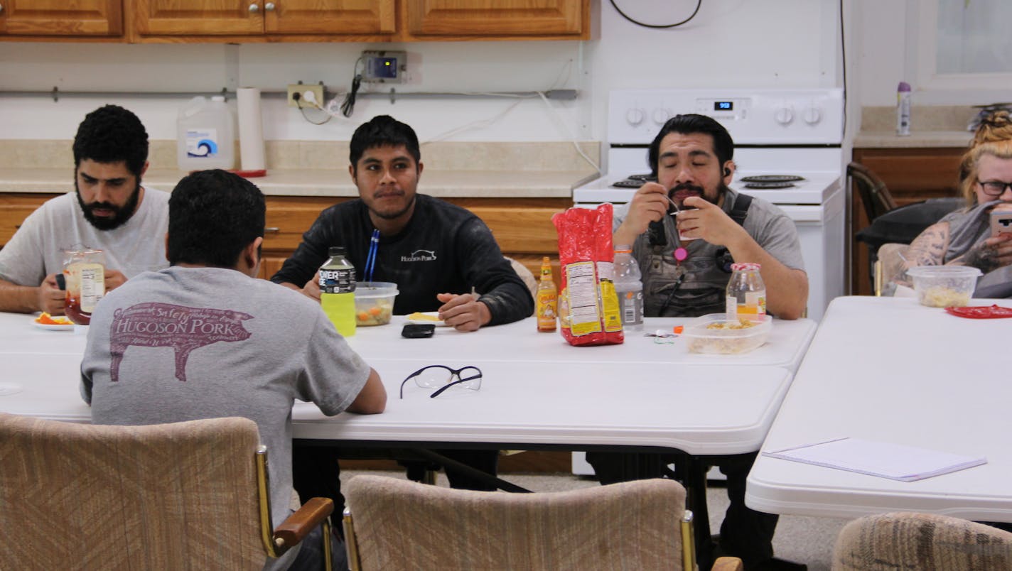 Josue Ramirez, left, and several other employees at Hugoson Pork take their lunch break at a sow barn near Granada, Minn. Ramirez, of Monterrey, Mexico, is in the United States on a trade national visa, which hog farmers and others in agriculture say are much-needed. They are also a little bit difficult to get, and approvals have slowed to a trickle during COVID.