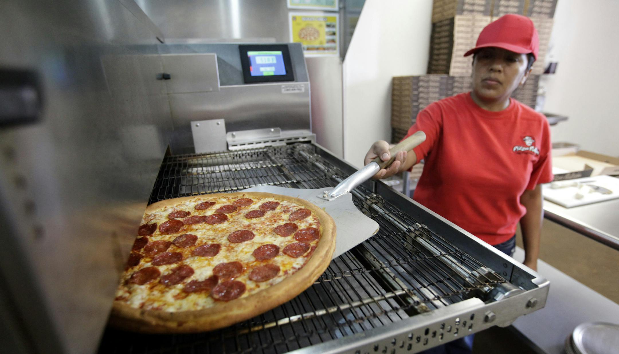 FILE - In this Thursday, May 24, 2012, file photo, employee Rosy Tirado pulls a pepperoni pizza from an oven at a Pizza Patron Dallas, Texas. While lower-wage American workers have accounted for the lion's share of the jobs created since the 2007-2009 Great Recession, a survey released March 2013 shows that they are also among the most pessimistic about their future career prospects, their job security and their finances. (AP Photo/Tony Gutierrez)