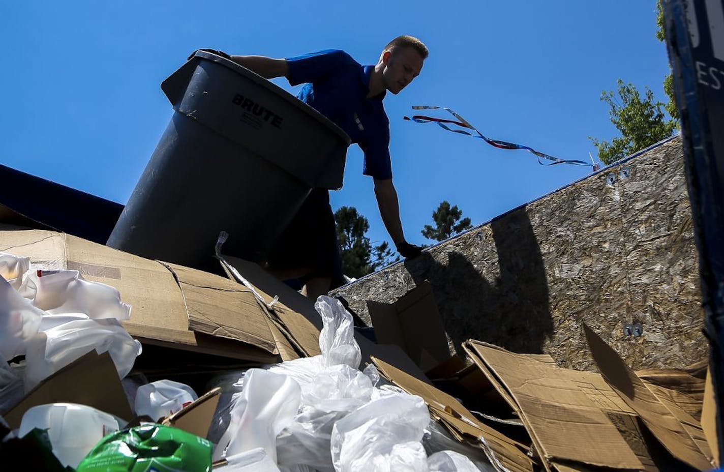 Ryan Hubner of 1-800-Got-Junk offloads a trashcan onto a garbage truck at the Lake Hiawatha cleanup spot.