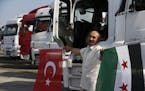 A truck driver poses for photographers in front of trucks carrying humanitarian aid destined for Idlib, Syria, by a Turkish pro-government aid group, 