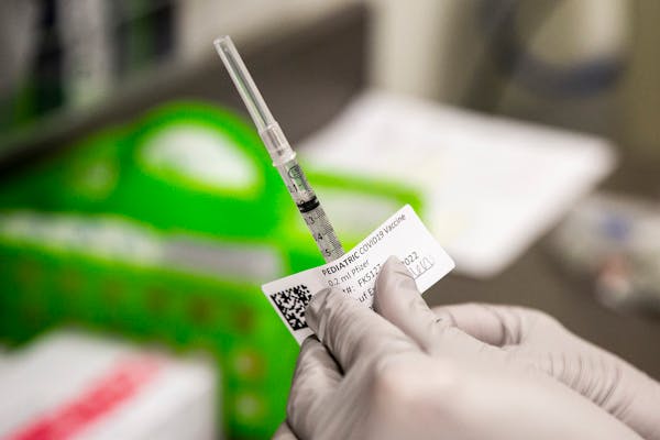 Jillian Berkan, a pharmacy resident at the University of Iowa Hospitals &amp; Clinics, places a label on a single dose of the Pfizer pediatric COVID-1