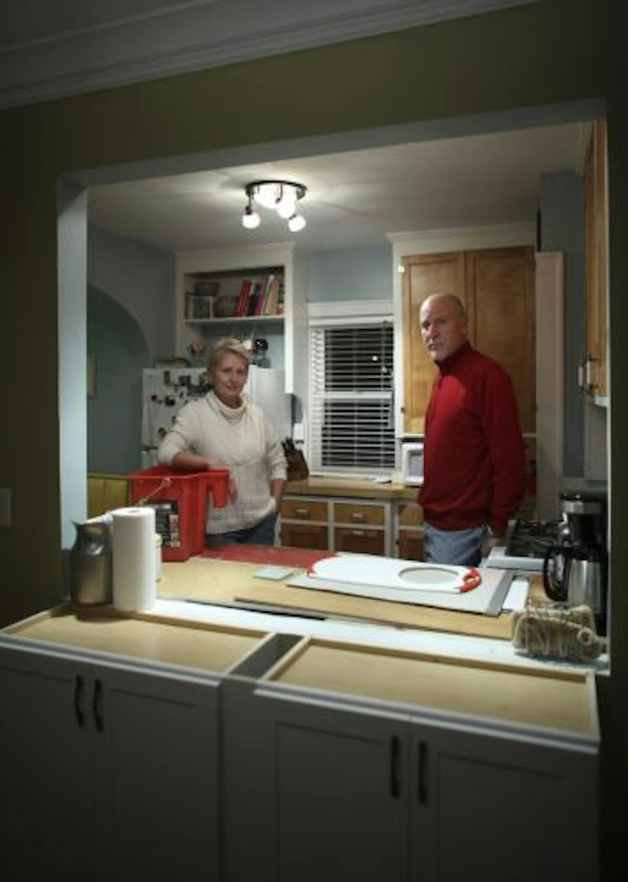 Colleen and Darrell Brandt in the kitchen of their Golden Valley home Friday night. They still await countertops and a sink to complete their kitchen remodel. They opened up the wall between the kitchen and dining room and had new cabinets installed in portion in the foreground. They use the bucket Colleen is leaning on to carry pots and pans to the bathroom for washing.