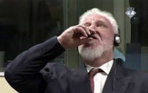 In this photo provided by the ICTY on Wednesday, Nov. 29, 2017, Slobodan Praljak brings a bottle to his lips, during a Yugoslav War Crimes Tribunal in