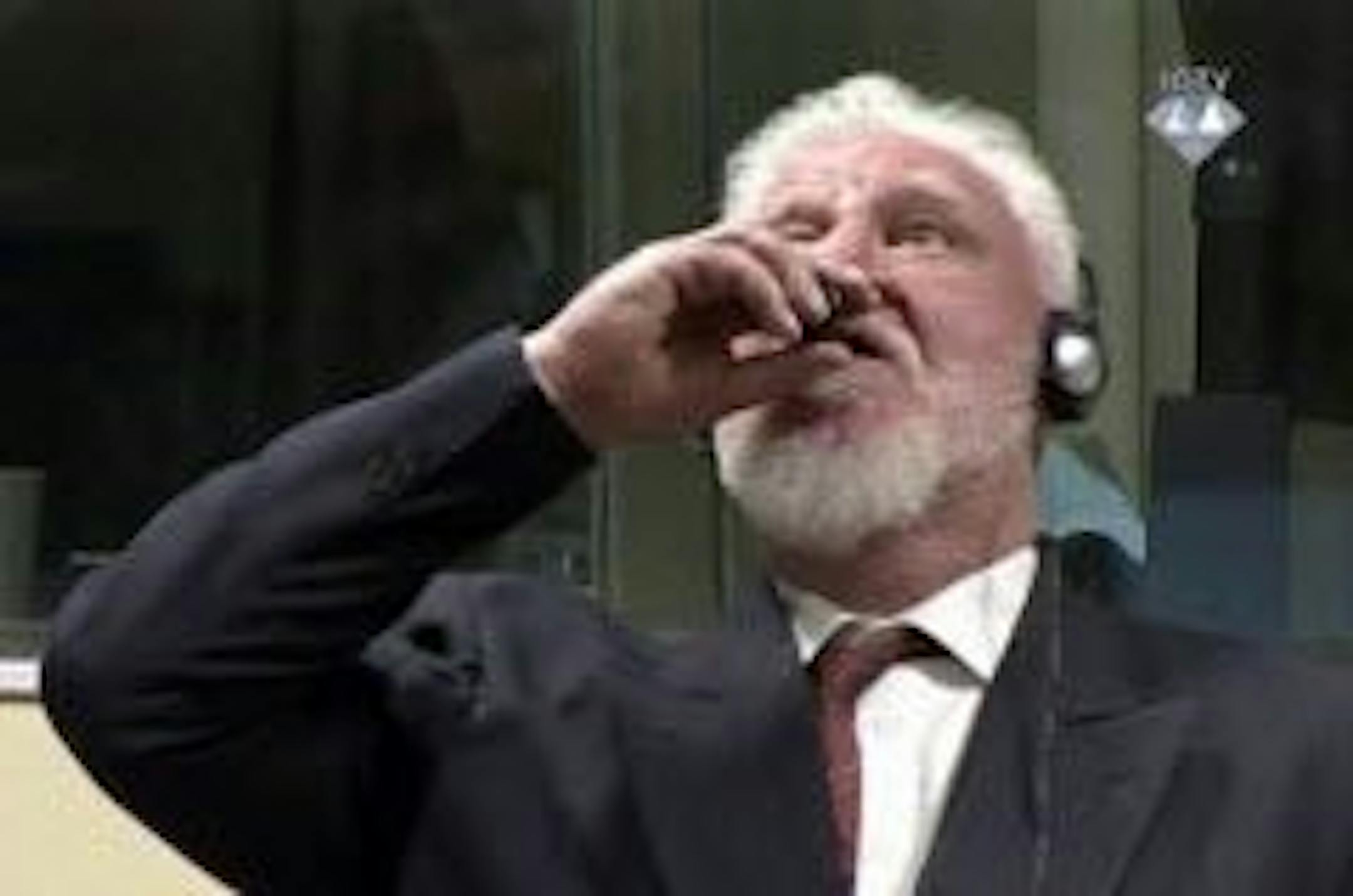 In this photo provided by the ICTY on Wednesday, Nov. 29, 2017, Slobodan Praljak brings a bottle to his lips, during a Yugoslav War Crimes Tribunal in The Hague, Netherlands. Praljak yelled, "I am not a war criminal!" and appeared to drink from a small bottle, seconds after judges reconfirmed his 20-year prison sentence for involvement in a campaign to drive Muslims out of a would-be Bosnian Croat ministate in Bosnia in the early 1990s.