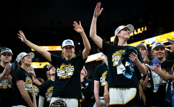 Iowa’s Kate Martin and Caitlin Clark wave to the crowd with their team after winning the Big Ten women’s basketball championship Sunday at Target 
