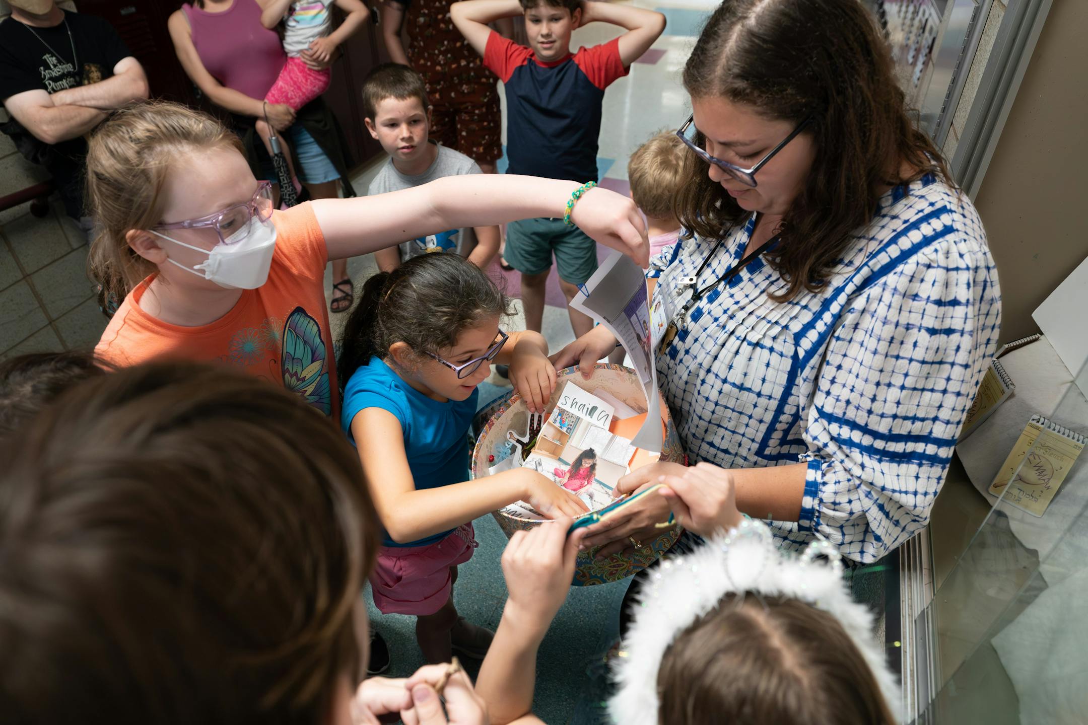 Principal Jessie Lavintman took the time capsule from its temporary display so the students could look inside one more time Friday, June 2, 2023 St. Paul, Minn. Students at the Newman School — part of Talmud Torah, a Jewish day school in St. Paul — built a time capsule on Friday. After learning about the history of the founders of their school, they're sending a little bit of their own history into the future.