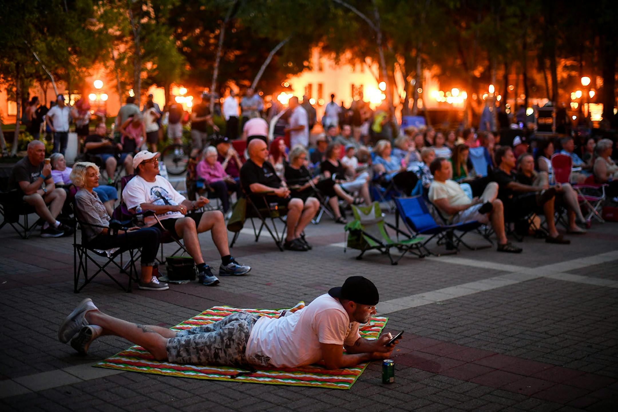 Justin Johnson, of St. Paul, checked his phone while his three daughters played nearby Thursday night at Mears Park.