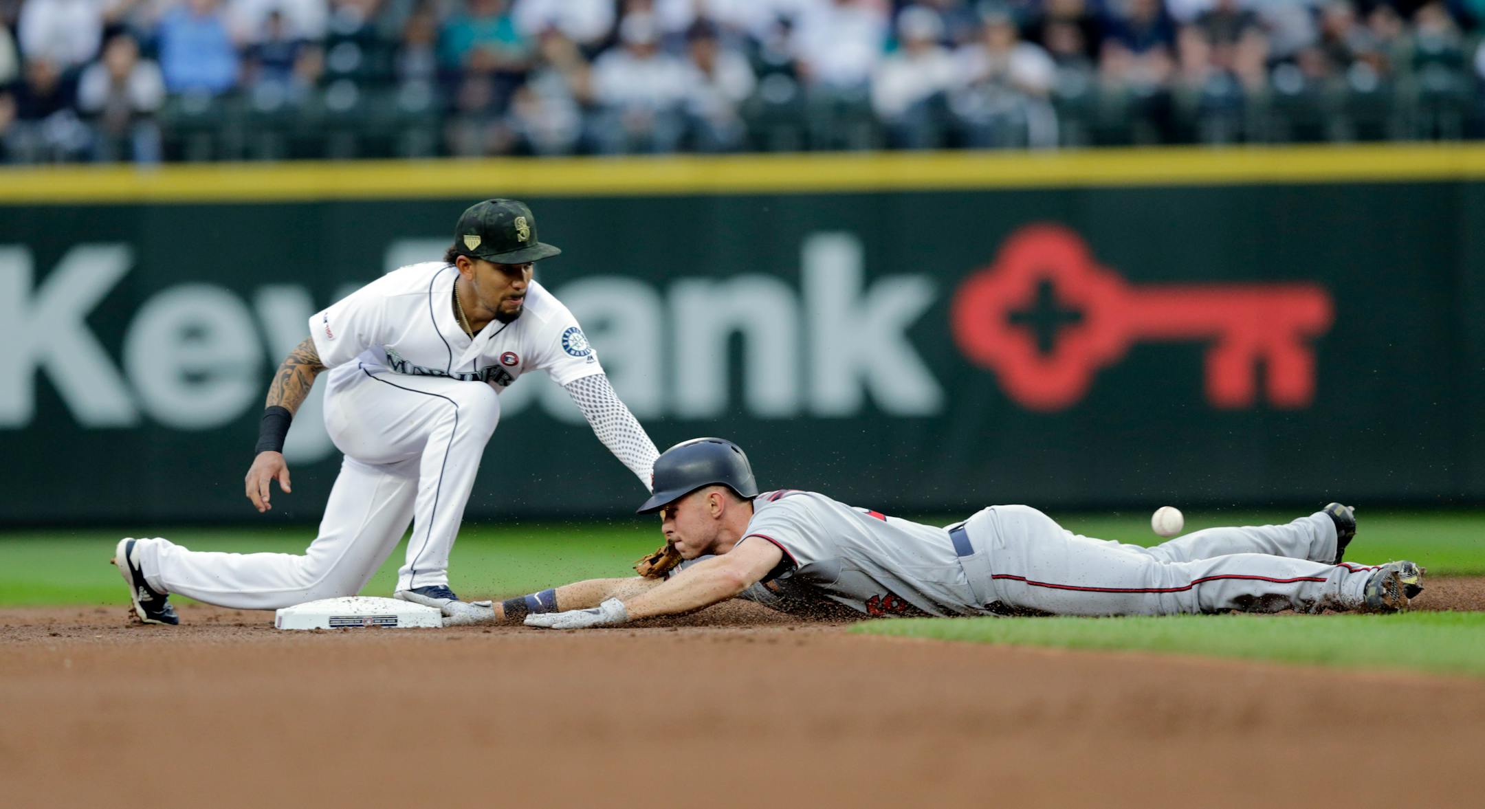 Minnesota Twins' Max Kepler slides safely into second for a double as Seattle Mariners shortstop J.P. Crawford applies a tag with the ball bouncing behind Kepler during the second inning a baseball game Saturday, May 18, 2019, in Seattle. (AP Photo/John Froschauer)