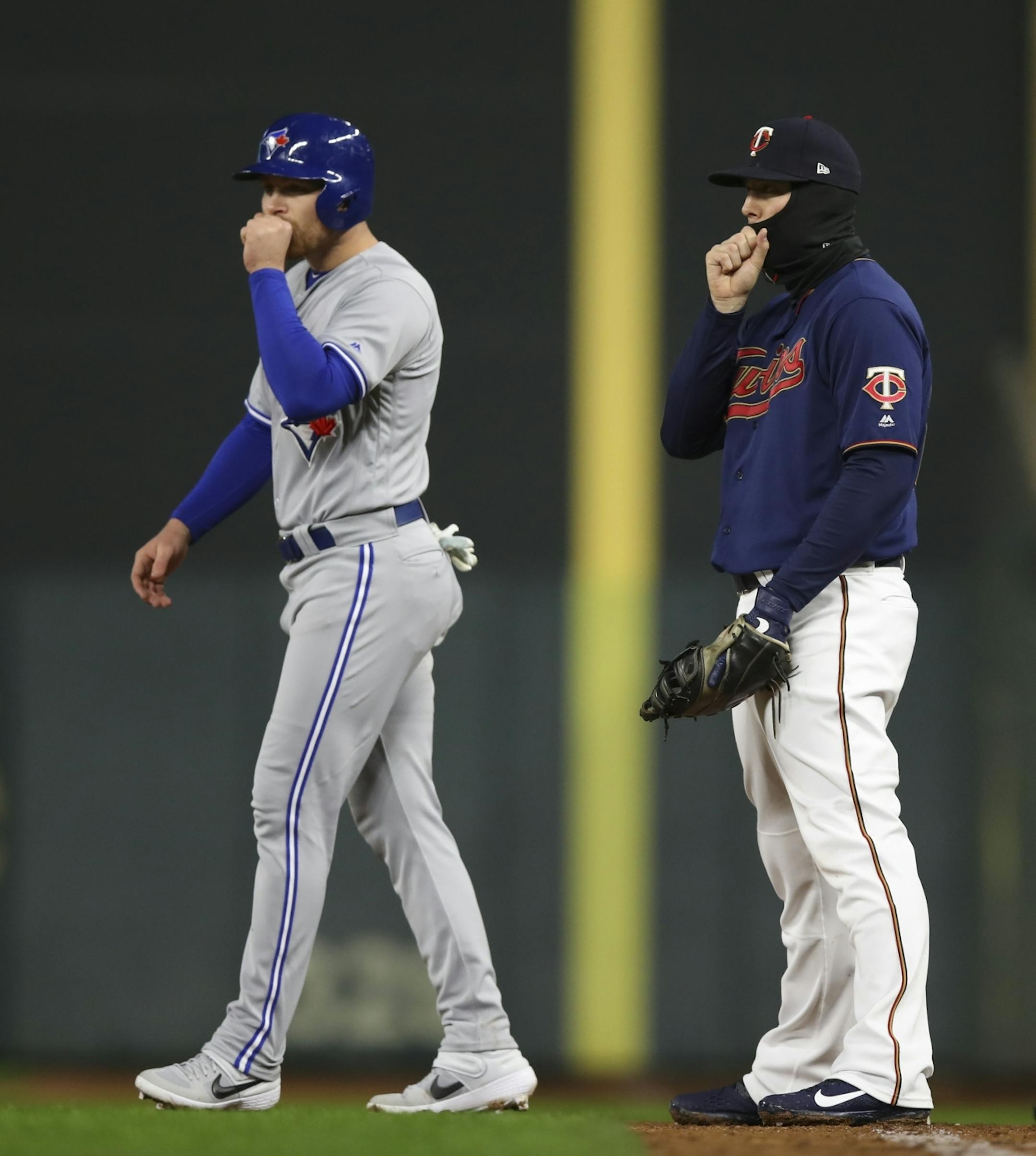 Toronto Blue Jays Brandon Drury, left, and Minnesota Twins first baseman C.J. Cron both tried to stay warm in the fourth inning.