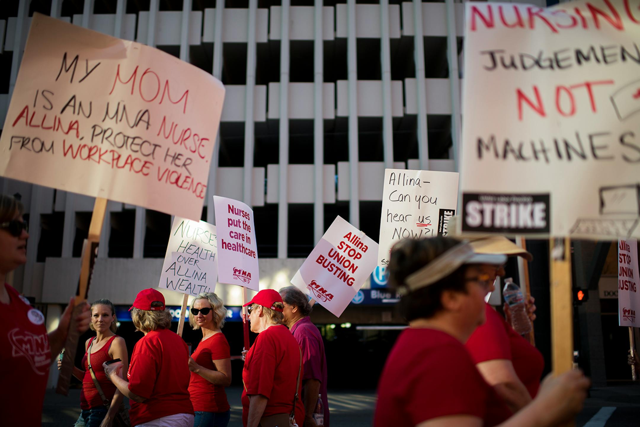 Picketers with various signs walk up and down the sidewalk in front of United Hospital in St. Paul on Sunday morning.