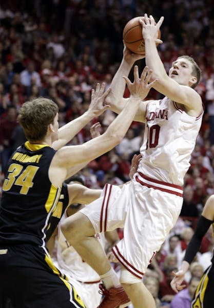 Indiana forward Cody Zeller, right, shoots over Iowa center Adam Woodbury in the second half of an NCAA college basketball game in Bloomington, Ind., 