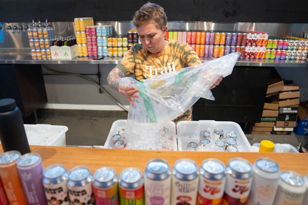 Abby Rouster pours ice on cans of THC-infused beverages during a media preview open house Wednesday, Dec. 14, 2022 at the Trail Magic Taproom Pop-Up i