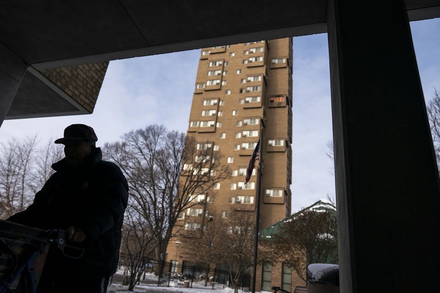 A resident walked through an outdoor plaza as Cedar High Apartments loomed in the background with boarded up windows where the fire damage was sustained.