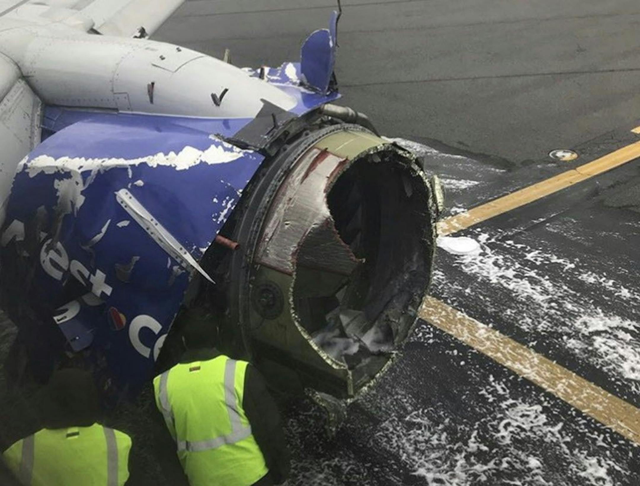 The engine on a Southwest Airlines plane is inspected as it sits on the runway at the Philadelphia International Airport after it made an emergency landing in Philadelphia, Tuesday, April 17, 2018.
