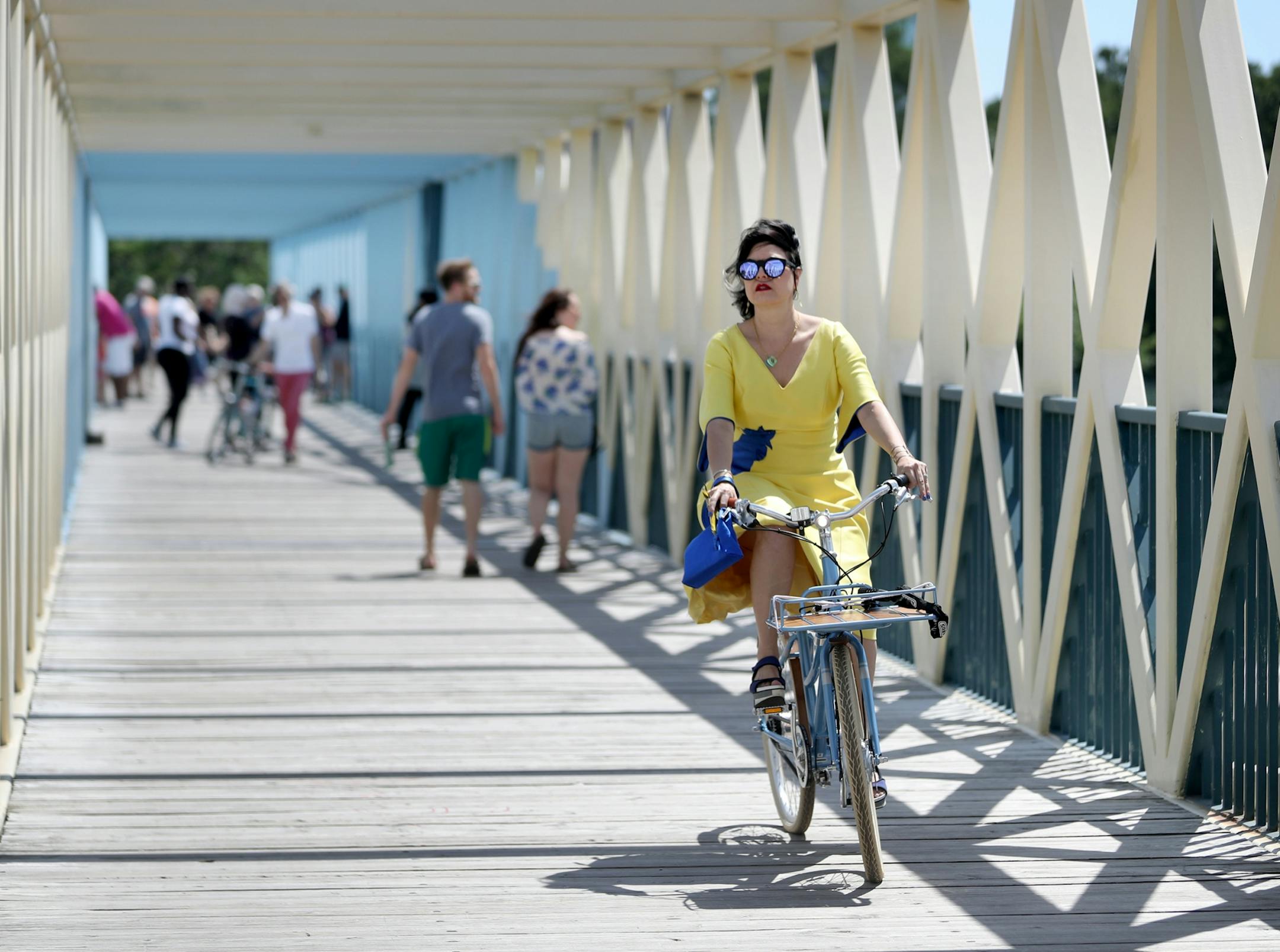 The re-opening of the Minneapolis Sculpture Garden unfolded on a windy, hot Saturday. Here, Nina Hale, a Walker Art Center board member, biked across a bridge to the site.