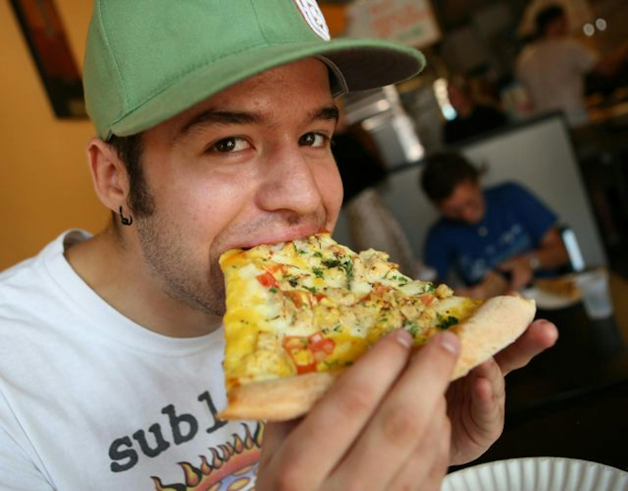 TOM WALLACE � twallace@startribune ASSIGN#113021_SLUG_rn0913.#113021_9/6/2007 Charlie Jude, Sartell MN, student at the University of MN takes a bite out of a slice Morlaya's Chicken from Mesa Pizza by the slice 1323 4th street SE.