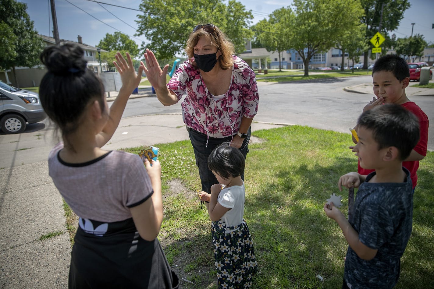 The Ramsey County Sheriff's outreach Cmdr. Mary Kay Skelly gave air high-fives to children after giving them freezes and stickers in the McDonough Homes neighborhood on July 3. The Sheriff's Office was also handing out face masks as part of a Help Team to provide essential items and assist those who are most at risk and vulnerable during the COVID-19 pandemic.