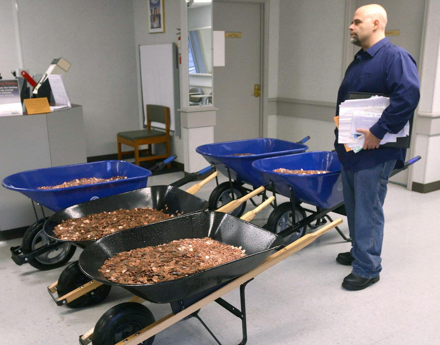 Nick Stafford waits for his number to be called Wednesday, Jan. 11, 2017, as he stands beside of 5 wheelbarrows full of change, mostly pennies, at the DMV in Lebanon, Va.