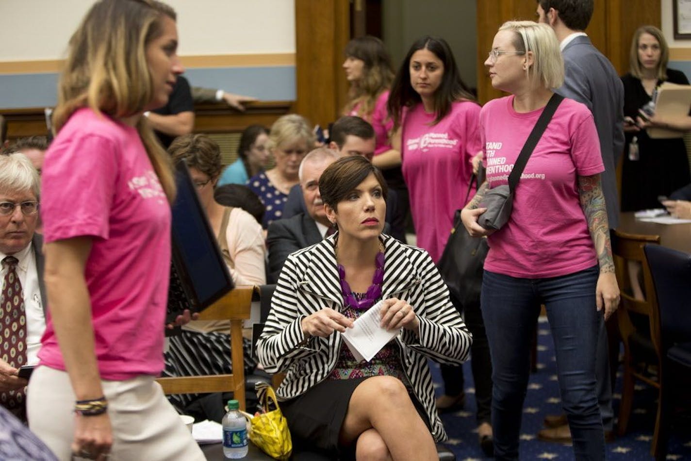 As supporters of Planned Parenthood looks for seats, Melissa Ohden, center, an anti-abortion activist from Gladstone, MO., waits to testify before the House Judiciary Committee hearing at the Capitol in Washington examining the abortion practices of Planned Parenthood, Wednesday, Sept. 9, 2015.