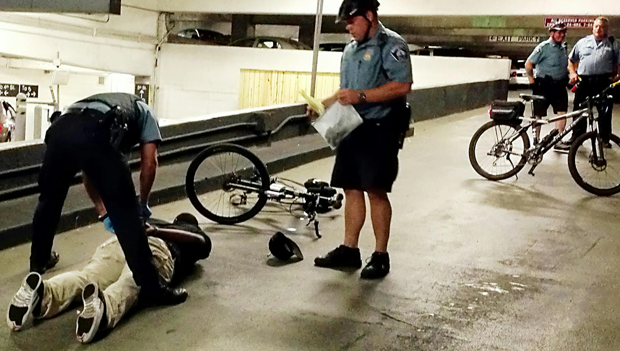 ERIC ROPER/ STAR TRIBUNE. Following a fight in a parking ramp across from the Gay 90s in downtown Minnepaolis, officer Shaun Harrington watches as another officer restrains one of the men involved in the fight. Confiscated drug paraphernalia can be seen on the ground.