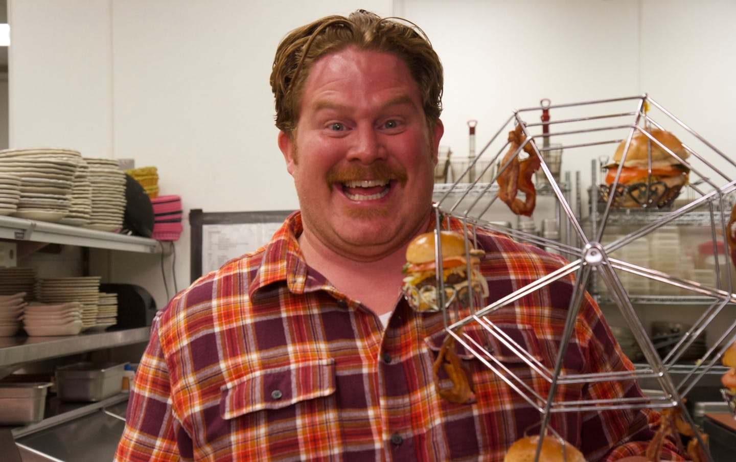 Host Casey Webb posing with the Brunching of Champions mini ferris wheel at Betty Danger's Country Club in Minneapolis, as seen on Travel Channel's "Man v. Food."