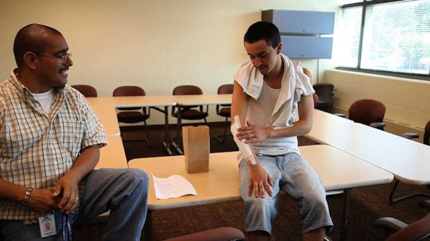 Albert Gomez touched his arm where one of his tattoos had been removed Monday afternoon, and chatted with Enrique Estrada, the youth and community advocate for Neighborhood House. Estrada has seen teens use lemons, sandpaper and blades to try to remove their tattoos.