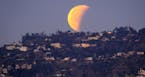 A super blue blood moon is seen setting behind the Hollywood hills in Los Angeles on Wednesday Jan. 31, 2018. The moon is putting on a rare cosmic sho