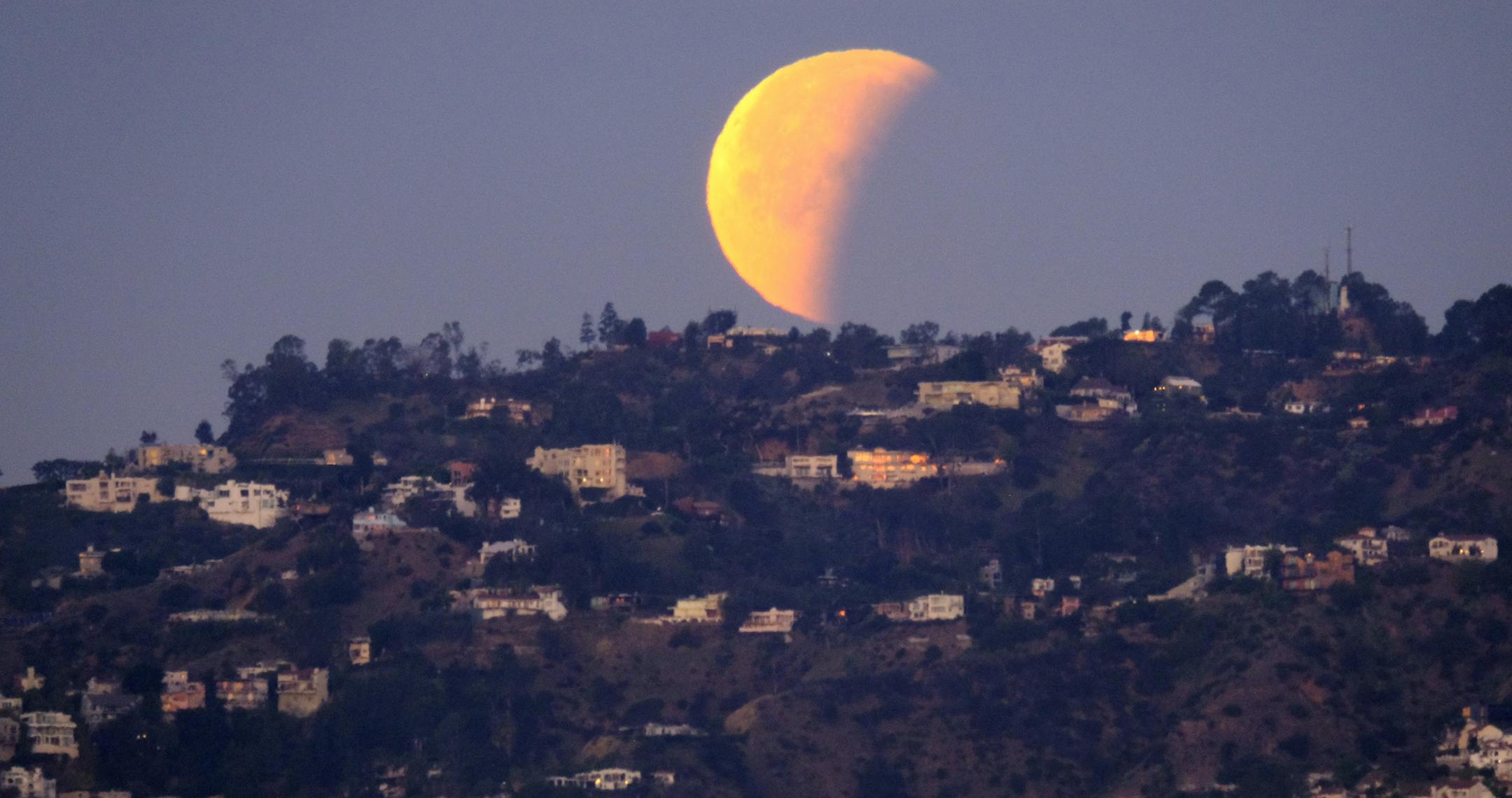 A super blue blood moon is seen setting behind the Hollywood hills in Los Angeles on Wednesday Jan. 31, 2018. The moon is putting on a rare cosmic show. It's the first time in 35 years a blue moon has synced up with a supermoon and a total lunar eclipse. NASA is calling it a lunar trifecta: the first super blue blood moon since 1982. That combination won't happen again until 2037. (AP Photo/Richard Vogel)