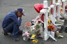 A man cries beside a cross at a makeshift memorial near the scene of a mass shooting at a shopping complex Tuesday, Aug. 6, 2019, in El Paso, Texas. T