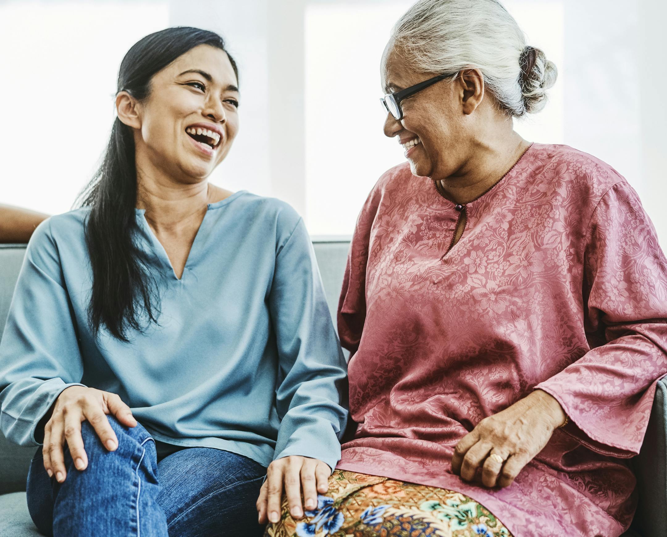 Happy mature woman sitting with mother-in-law on sofa. Females are talking in living room. They are spending leisure time. ORG XMIT: 775109147