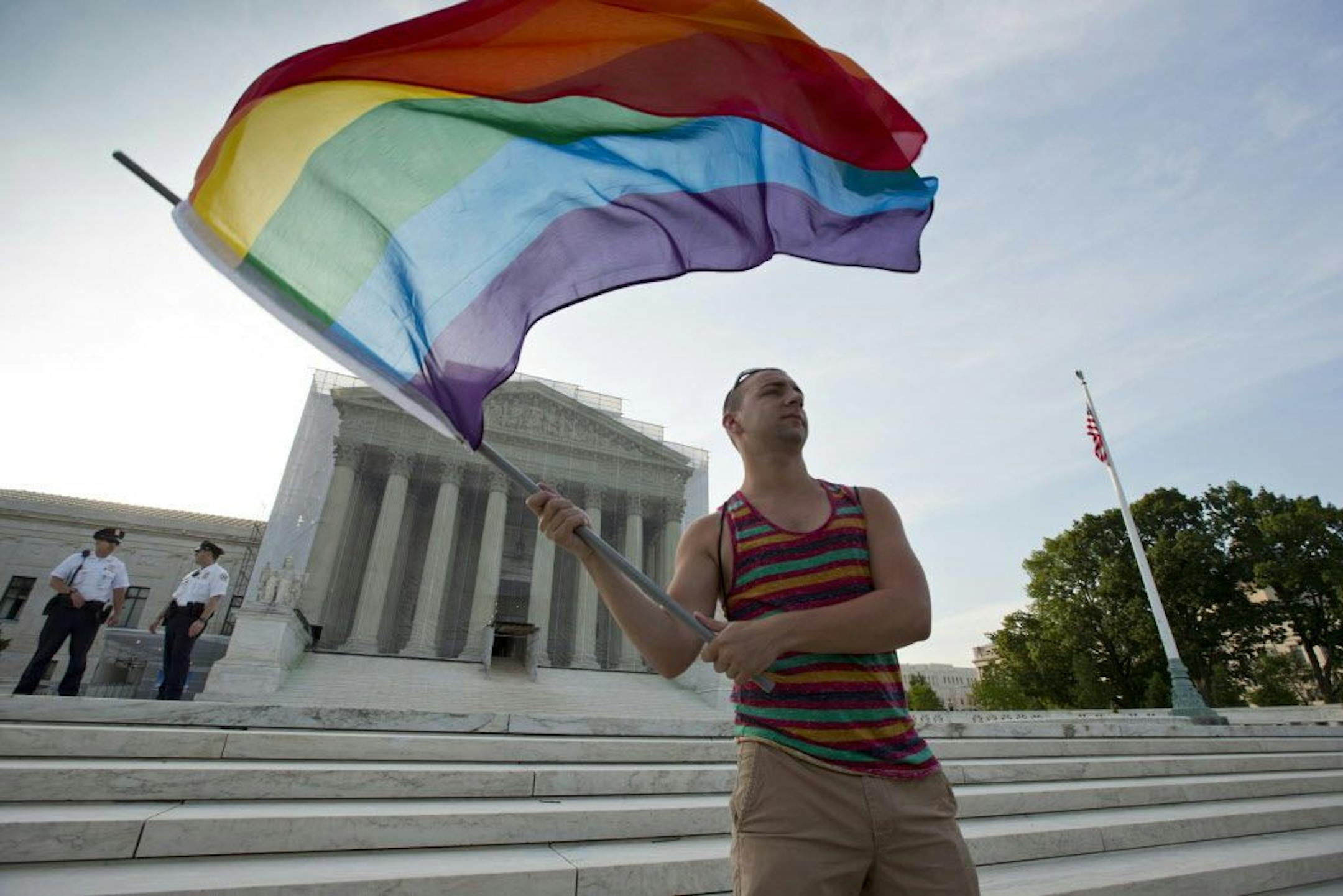 FILE- In this June 26, 2013 file photo, gay rights advocate Vin Testa waves a rainbow flag in front of the Supreme Court in Washington. Both sides in the gay marriage debate agree on one thing: It�s time for the Supreme Court to settle the matter. Even a justice said recently that she thinks so, too. That emerging consensus makes it likely that the justices soon will agree to take up the question of whether the Constitution forbids states from defining marriage as the union of a man and a woman.