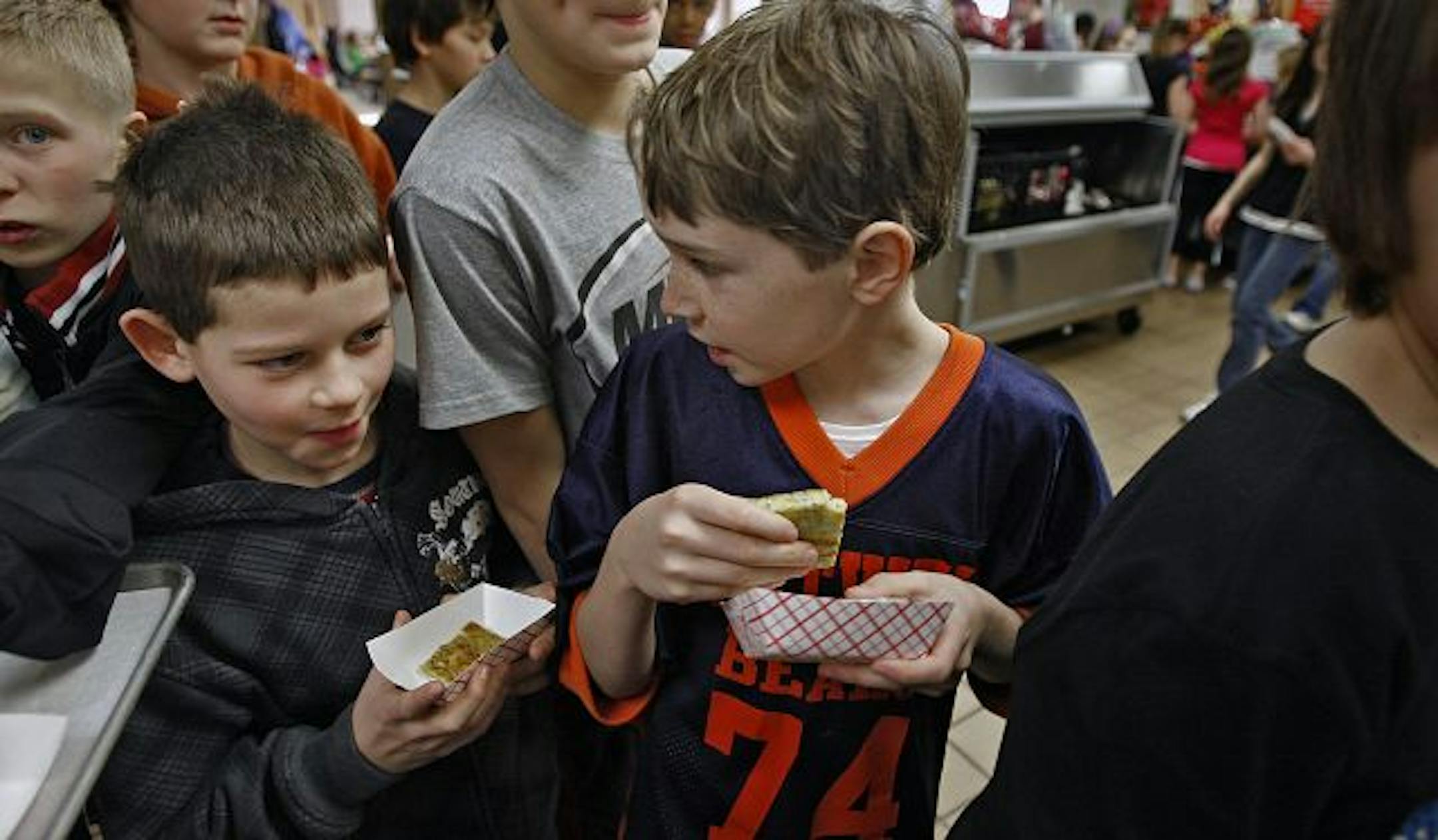 Go ahead, take a bite: Sterling Krim, 11 (right), and Logan Loebrick, 12, examined the zucchini egg bake offered to them by student chefs as a way to get youngsters to eat the suspicious vegetable.