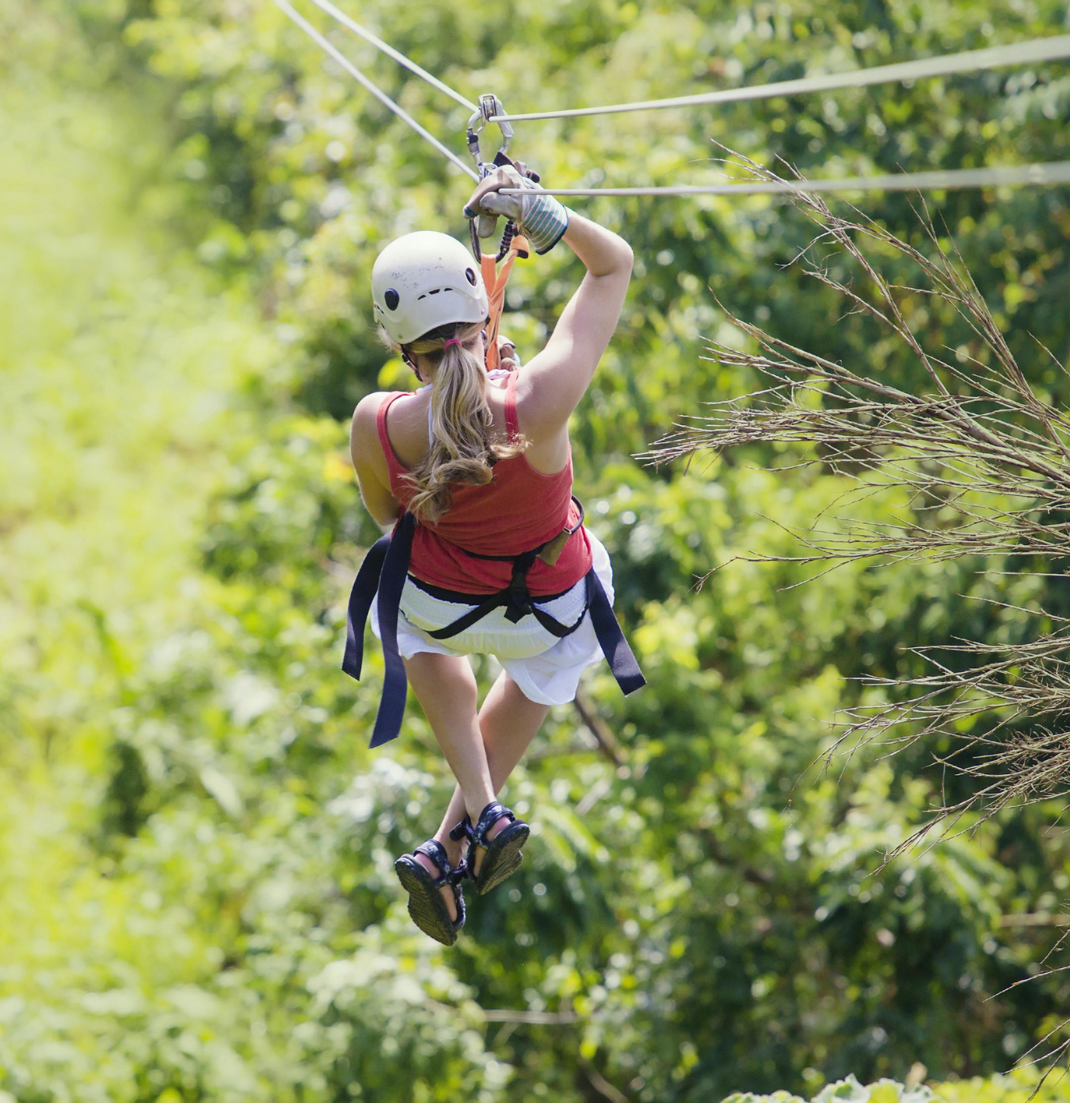 Woman enjoying a fun zip line tour in the jungle while on vacation
