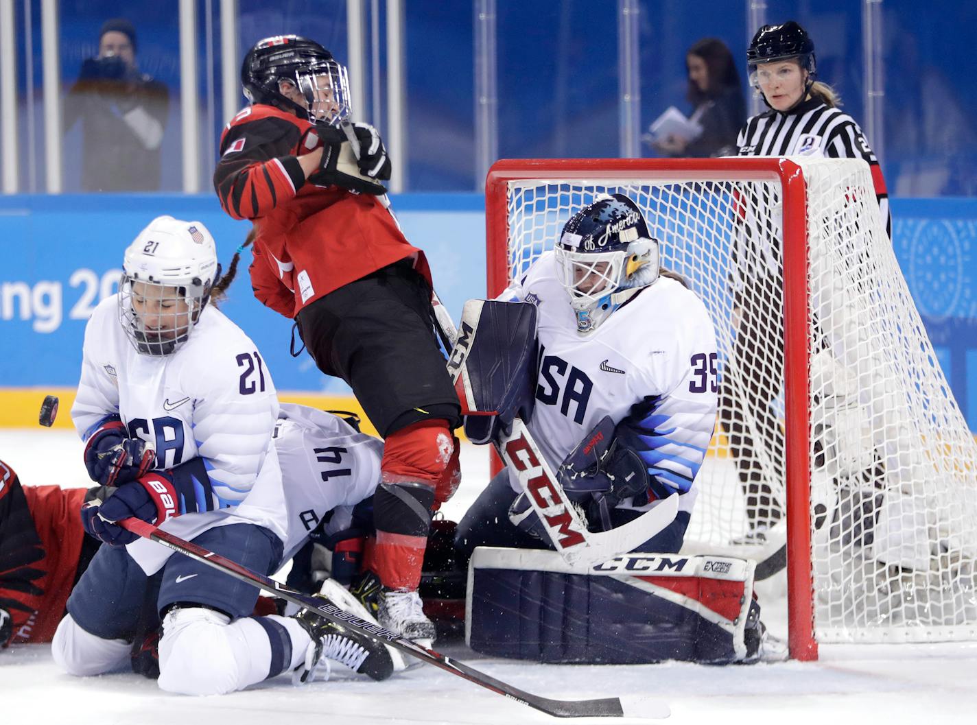 Hilary Knight, left, of the United States, blocks a shot by Canada as goalie goalie Maddie Rooney, right, protects her net against Canada's Melodie Daoust