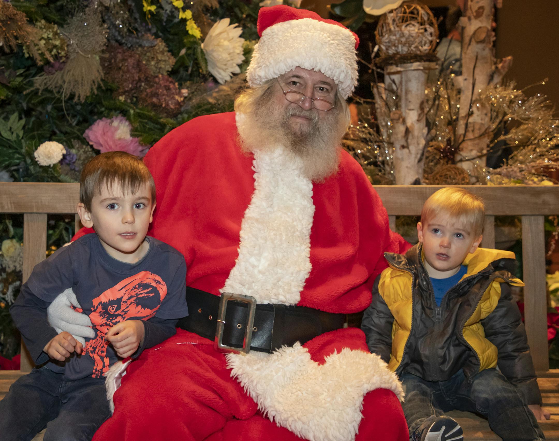 Connor and Charlie sit with Santa at the 2019 Winter in Bloom exhibit at the Minnesota Landscape Arboretum. [ Special to Star Tribune, photo by Matt Blewett, Matte B Photography, matt@mattebphoto.com, Minnesota Landscape Arboretum, Winter in Bloom, Minnesota, SAXO 1009874394 FACE120819 Santa's name: Bob Thorn (retired Arboretum employee - he built the poinsettia tree that they lit tonight. Andy Goke, Connor and Charlie's dad, gave permission.