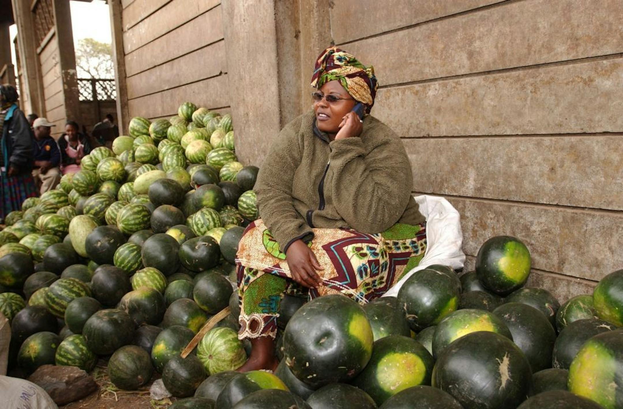 A woman spoke on a cell phone while selling watermelons in Nairobi, Kenya.
