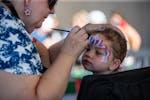 Ahead of fireworks Wednesday night at Canterbury Park in Shakopee, Anita Beal paints Giordana Masci’s face.