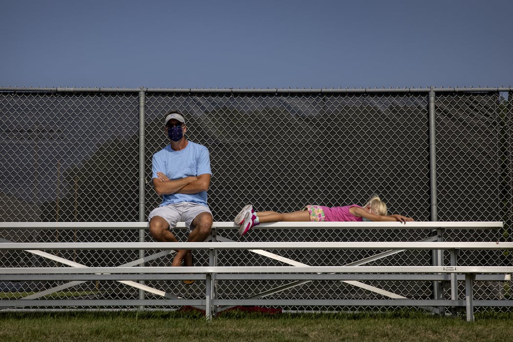 Andrew Werner and his daughter Lola, 5, watched the Blake and Minnetonka girls' tennis match from the social distantly marked bleachers. Werner is a teacher at Minnetonka High School.