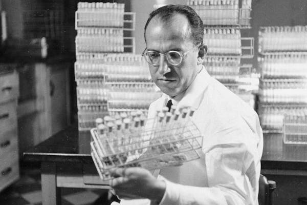 FILE - In this Oct. 7, 1954, file photo, Dr. Jonas Salk, developer of the polio vaccine, holds a rack of test tubes in his lab in Pittsburgh. Peter Sa