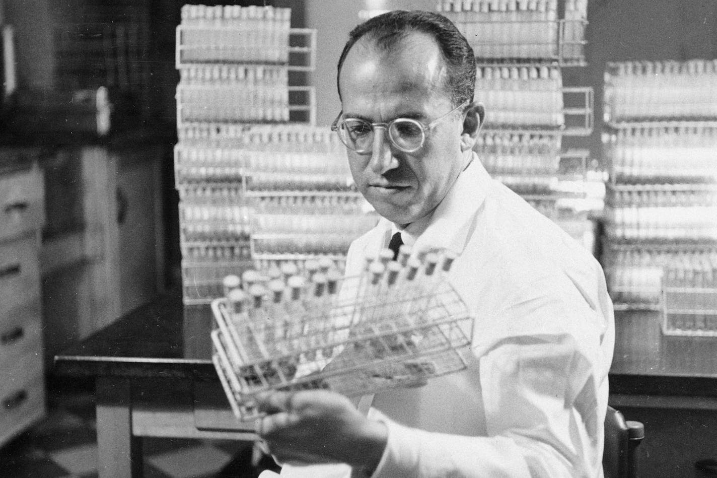 FILE - In this Oct. 7, 1954, file photo, Dr. Jonas Salk, developer of the polio vaccine, holds a rack of test tubes in his lab in Pittsburgh. Peter Salk still remembers the trepidation he felt when his father came home from work one day in May 1953 and promptly began boiling a set of needles and syringes on the kitchen stove. With several years of research and promising results in monkeys fueling high hopes, Dr. Jonas Salk had brought from his lab at the University of Pittsburgh a still-experime