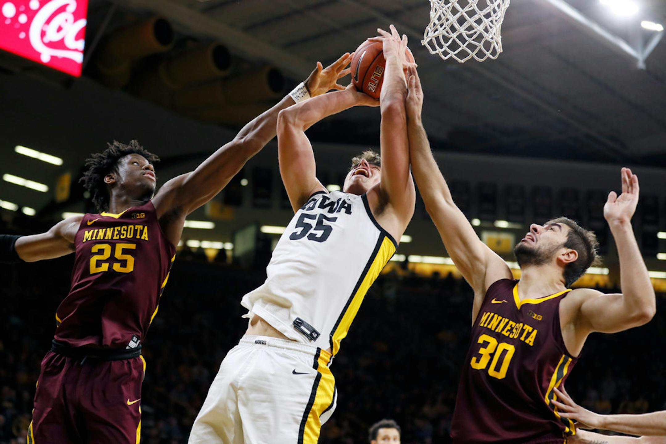 Iowa center Luka Garza, center, drives to the basket between Minnesota's Daniel Oturu, left, and Alihan Demir, right, during the second half