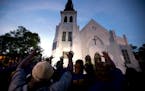 The men of Omega Psi Phi Fraternity Inc. lead a crowd of people in prayer outside the Emanuel AME Church, Friday, June 19, 2015, after a memorial in C
