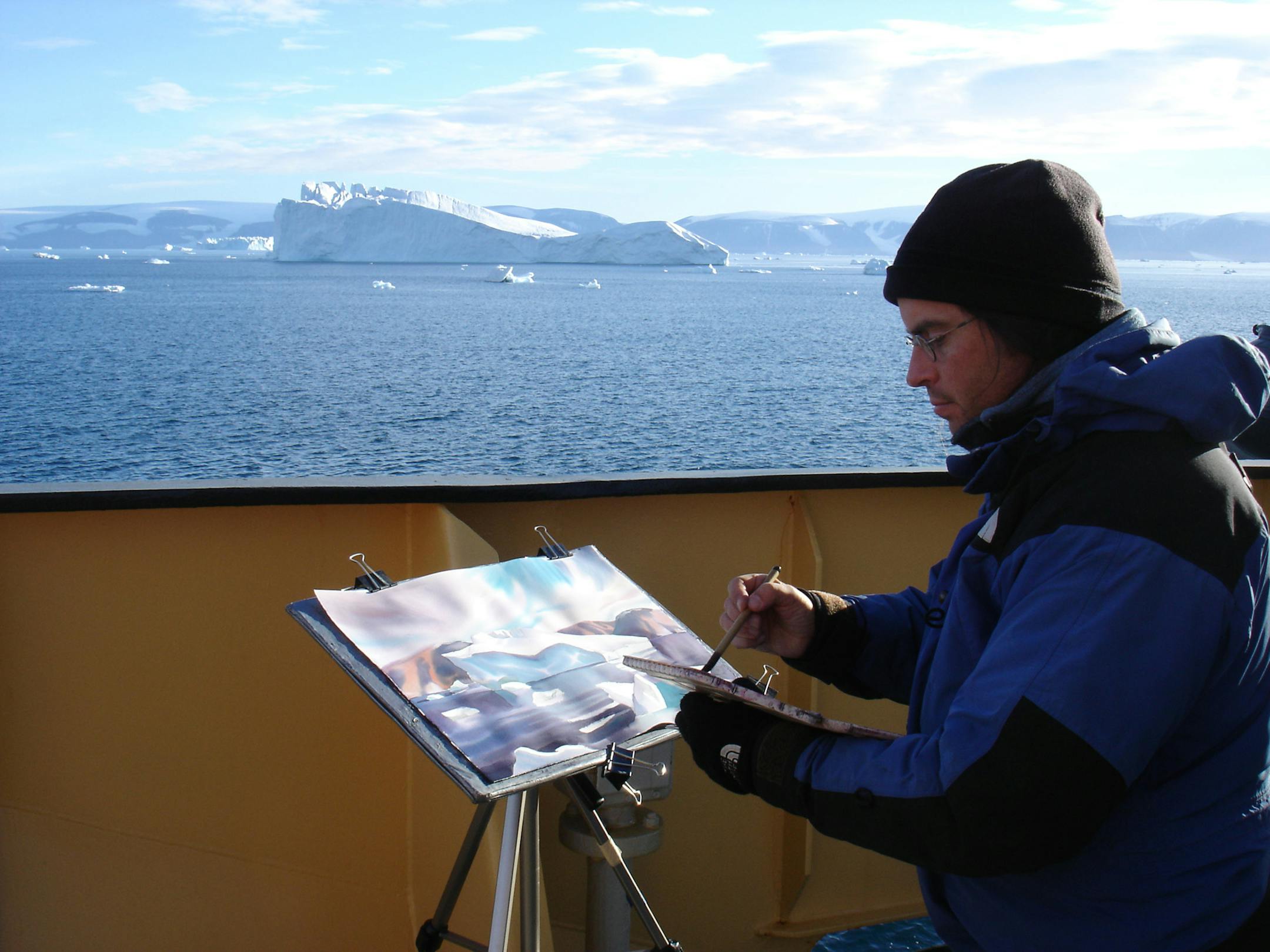 David McEown, artist in residence onboard the Kapitan Khlebnikov, ignores the cold near the prow of the ship to work on a wintery watercolor.
