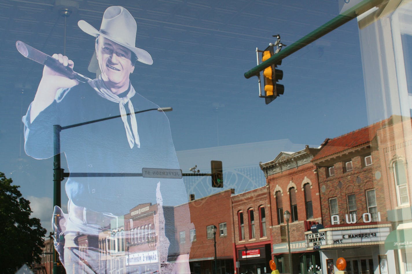 The reflection of a John Wayne figure is seen in the window of the Chamner of Commerce in Winterset, Iowa, his birthplace. (Alan Solomon/Chicago Tribune/MCT)